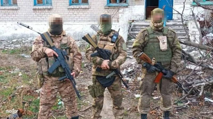 Armed men in camouflage against the backdrop of ruins