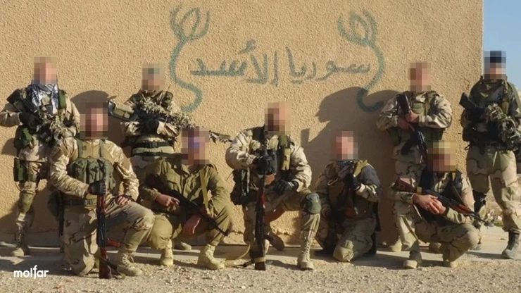 Group of armed men near a wall with Arabic inscription